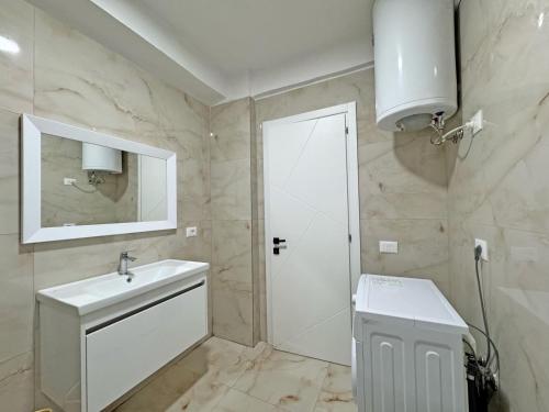 a white bathroom with a sink and a mirror at Ilir Daily Rent in Durrës