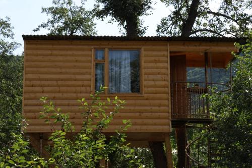 a log cabin in the woods with a balcony at Tree House & Camping Goris in Goris