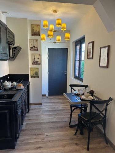 una cocina con mesa y sillas y una puerta azul en STUDIO VOYAGE COLONIAL CLIMATISE chic, en Beauvais