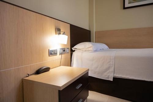 a hotel room with a bed and a telephone at Hotel Flamingo in L'Ampolla