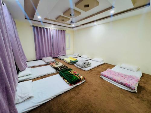 a room with four beds and purple curtains at Zim Zim &Salaar Gust House in Skardu