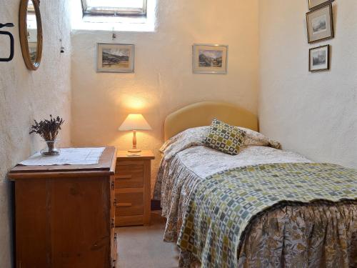 a bedroom with a bed and a table with a lamp at Ty Christian in Blaencelyn