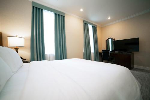 a hotel room with a white bed and a television at Hotel Stanford in New York