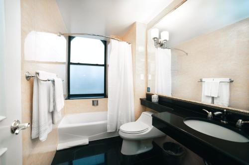 Un baño con inodoro, lavabo y ventana. en Hotel Stanford, en Nueva York