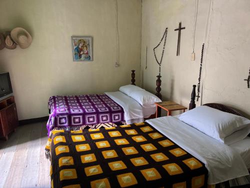 a room with three beds and a cross on the wall at Casa colonial con encanto en Sonsón in Sonsón