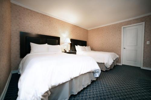 two beds in a hotel room with white sheets at Hotel Stanford in New York