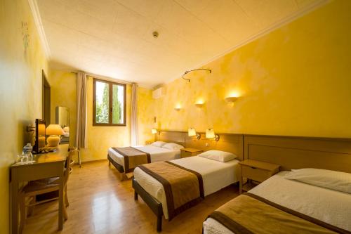 a hotel room with two beds and a desk at Hôtel La Bonne Auberge in Moustiers-Sainte-Marie