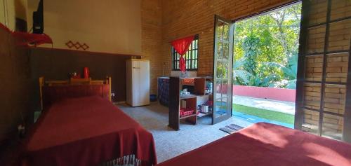 Habitación con 2 camas y puerta corredera de cristal en Tahoma Chale Rustico côr Café e vermelho Prumirim Paraiso, en Ubatuba