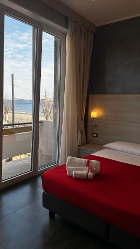 a bedroom with a bed with a red blanket and a large window at B&B Margherita in Messina