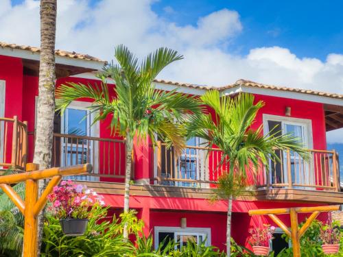 a red house with palm trees in front of it at Pousada Vila das Velas in Ilhabela