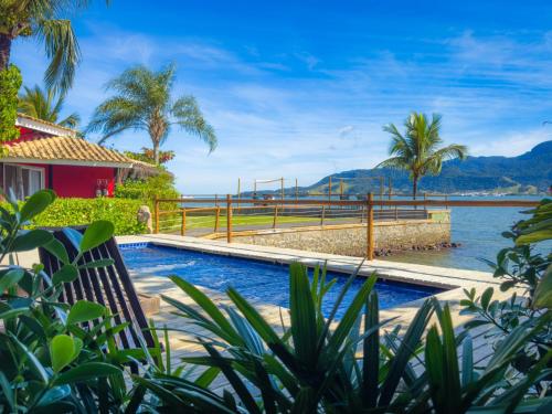 a resort pool with a view of the water at Pousada Vila das Velas in Ilhabela