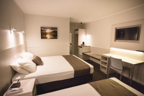 una camera d'albergo con 2 letti e una scrivania di Wanaka Hotel a Wanaka