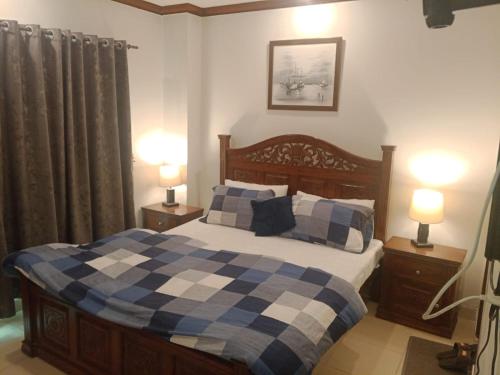 a bedroom with a bed with a blue and white checked blanket at muskan resort bhourbun in Murree