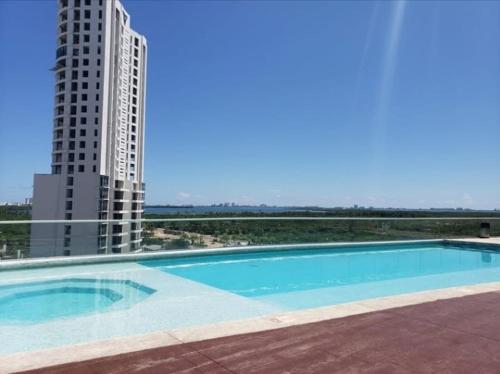 a large swimming pool next to a tall building at Apartment with a view of the lagoon and pool in Cancún