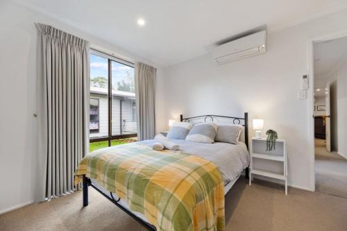 una camera da letto con un letto e una grande finestra di Inverloch Dual Retreat with Spa Bath 400m to Beach a Inverloch