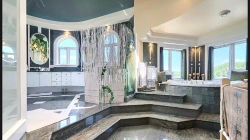 La salle de bains spacieuse est pourvue d'une grande baignoire et d'une douche. dans l'établissement Lakefront Wellness Estate - Pool, Sauna and Hot Tub, à Lac-Simon