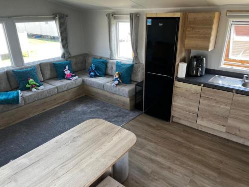 a living room with couches and a kitchen in a caravan at SBL57 - Parkdean, Camber Sands in Camber