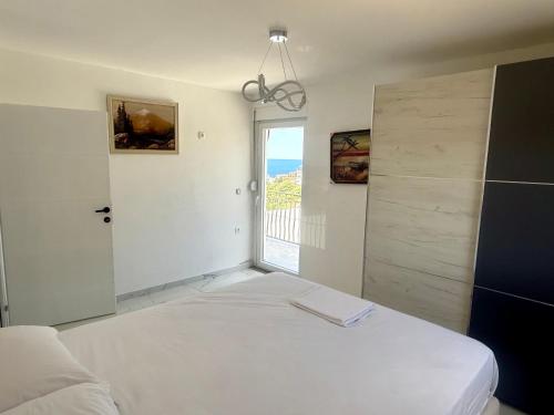 a white bedroom with a bed and a window at Azure View in Dobra Voda