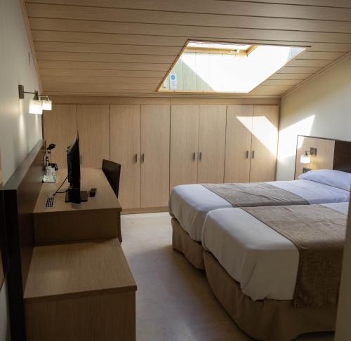 a bedroom with a bed and a desk with a television at Hotel Flamingo in L'Ampolla