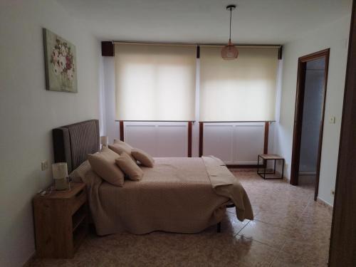 a bedroom with a bed and two large windows at Vivienda 2 sin ascensor in Laxe