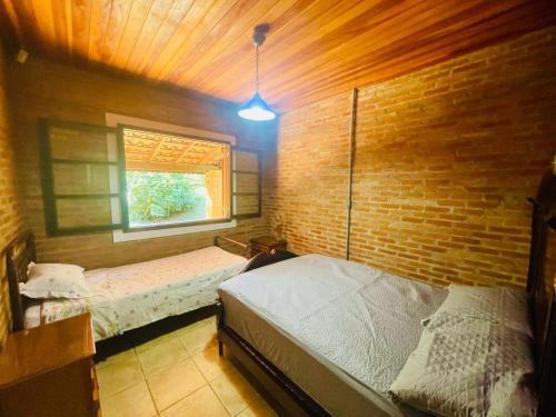 a bedroom with two beds and a brick wall at Pousada Nascente da Pedra in Pedra Bela
