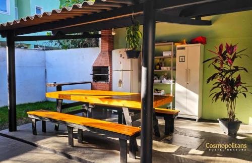 a picnic table with two benches and a refrigerator at Cosmopolitans Hostel in Ubatuba