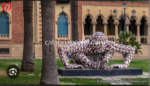 une statue d'un homme assis sur un banc devant un bâtiment dans l'établissement B&b sul corso, à Reggio de Calabre