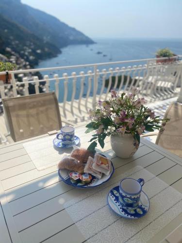 a table with two cups and plates of food on a balcony at Casa Donna Concetta in Positano