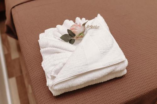 a white towel with a flower on a bed at Casa da Coruja in Rio de Janeiro