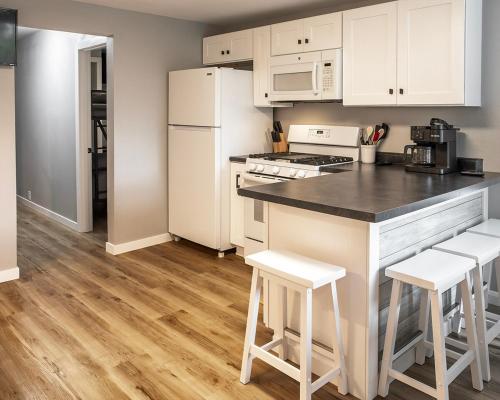 a kitchen with white cabinets and a counter with stools at Parkside Pet Friendly Bungalow in Winona