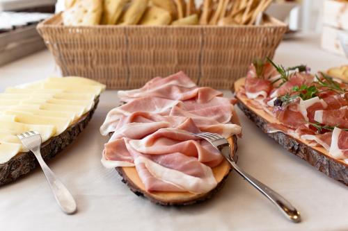 a sandwich with meat and cheese on a table with two forks at Hotel Stella Della Versilia in Marina di Massa