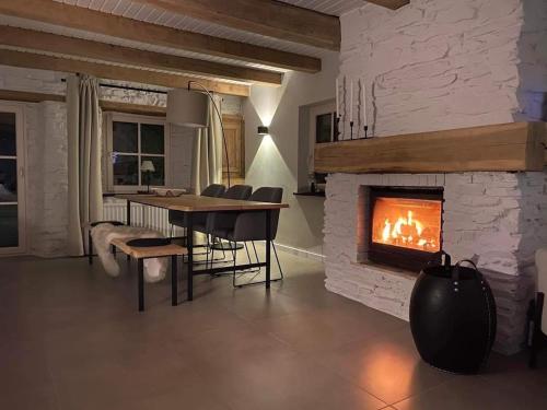 a living room with a fireplace and a table and chairs at CottageChristine in Vaux-sur-Sûre