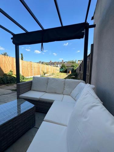 a white couch sitting under a canopy on a patio at Luxury House in Ilford 21 minute Train journey from Central London in Ilford