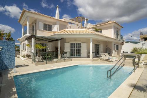 a villa with a swimming pool in front of a house at LV Premier Algarve FU1- pool, AC, garden, sea view in Moncarapacho