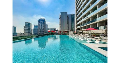 - une piscine avec des chaises blanches et une vue sur la ville dans l'établissement Stylish Studio - 5-min walk Burj Khalifa & Dubai Mall, à Dubaï