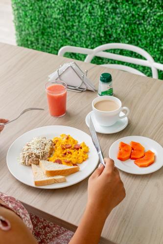 a person cutting a plate of breakfast food on a table at Hotel Aguamarina in Santa Marta
