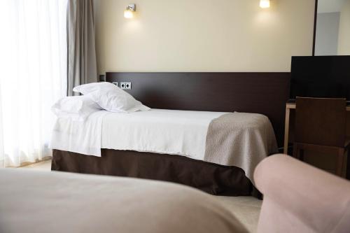a hotel room with two beds and a window at Hotel Flamingo in L'Ampolla