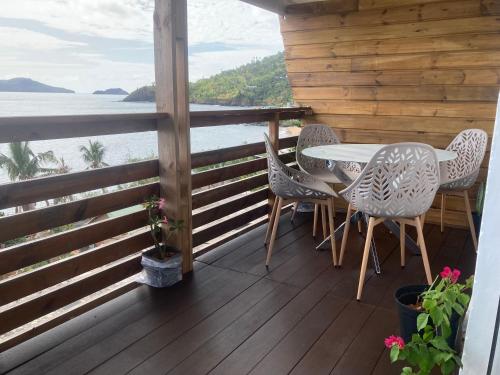a porch with a table and chairs and a view of the ocean at Coin paisible du nord in Acoua