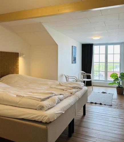 a bedroom with a large bed and a large window at Hotel Klitbakken in Løkken