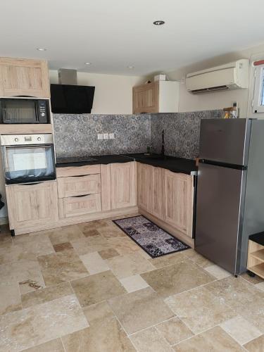 a kitchen with wooden cabinets and a stainless steel refrigerator at Gîte Drôme des collines in Anneyron