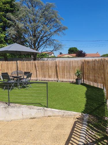a backyard with a table and an umbrella and a fence at Gîte Drôme des collines in Anneyron