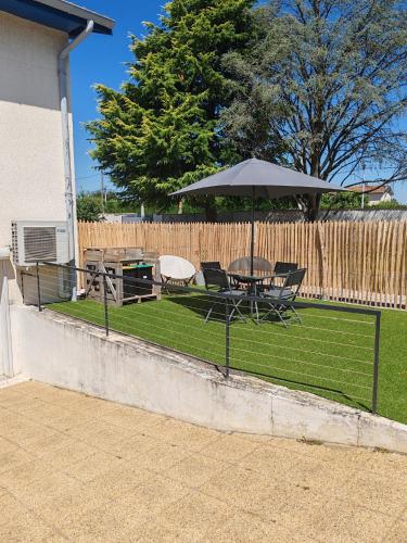 a table and chairs and an umbrella on a lawn at Gîte Drôme des collines in Anneyron