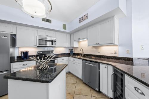 a kitchen with white cabinets and black counter tops at Pelican Pointe 506 in Orange Beach