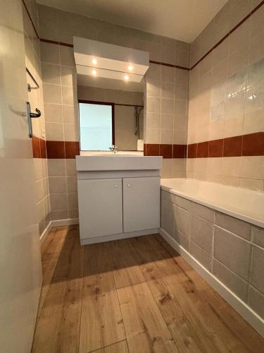 une salle de bain avec une baignoire, un lavabo et un miroir dans l'établissement Résidence Les Chalets de Puy Saint Vincent - maeva Home - Appartement 2 Pièces 4 Personnes - Confort MAE-6369, à Narreyroux