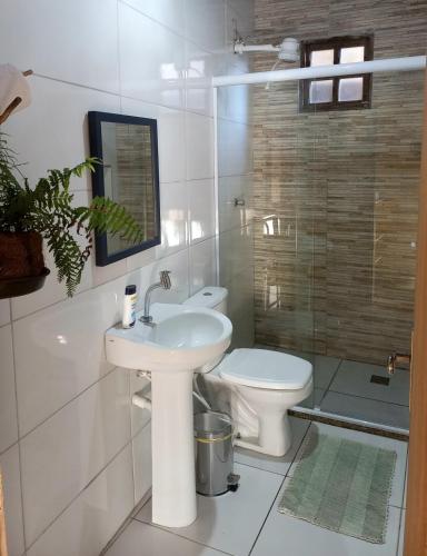 a white bathroom with a sink and a toilet at Casa de Cristal - Vila de Igatu in Andaraí