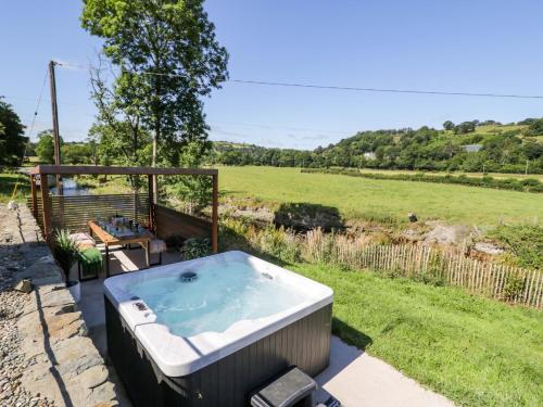 a hot tub in a yard with a field at Plas Glan Yr Afon in Abergele