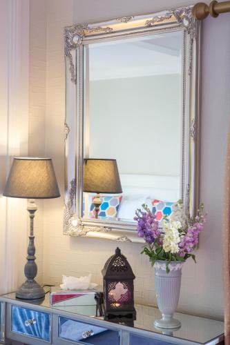 a mirror and a lamp and a vase with flowers on a dresser at Whitford House Hotel in Wexford