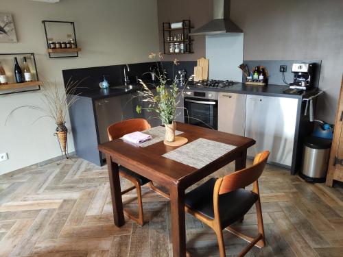 une cuisine avec une table et des chaises en bois et une cuisine avec des appareils en acier inoxydable dans l'établissement Gîte Côté Nature, à Cabrerolles
