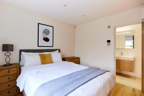 een slaapkamer met een groot wit bed en een badkamer bij The Bayswater Nook - Stylish 1BDR Flat in Londen