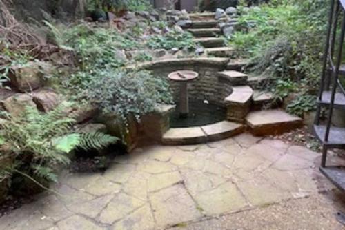 een tuin met een stenen pad en een fontein bij The Bayswater Nook - Stylish 1BDR Flat in Londen